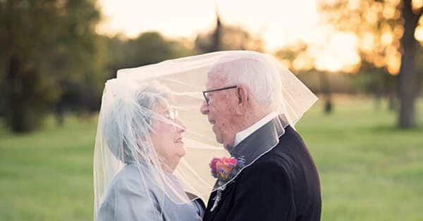 Casal de senhores idosos, em que a senhora está com um véu que ela colocou em cima da cabeça dela e dele