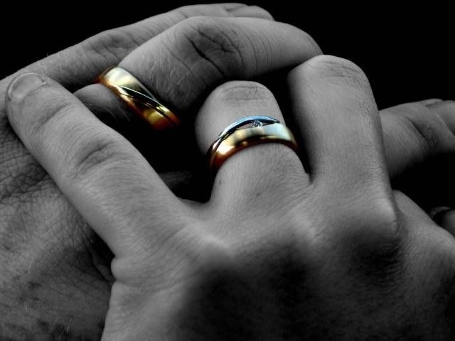 Foto em preto e branco da mão de um casal usando alianças