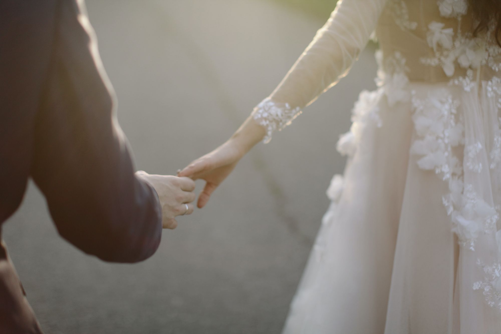Foto de noivos segurando a mão um do outro de forma suave.