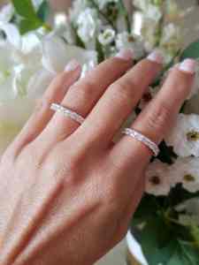 Foto de mão de mulher sobre buquê de flores para mostrar o modelo do anel da eternidade.
