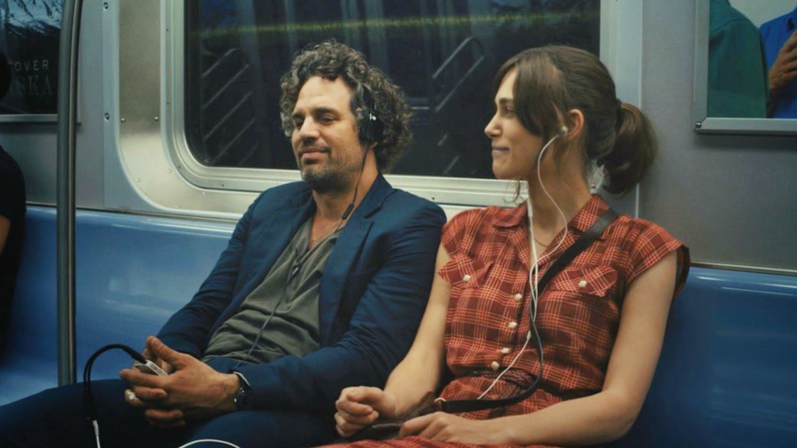 Cena do filme em que os personagens estão sentado nos metrô compartilhando os fones de ouvido.