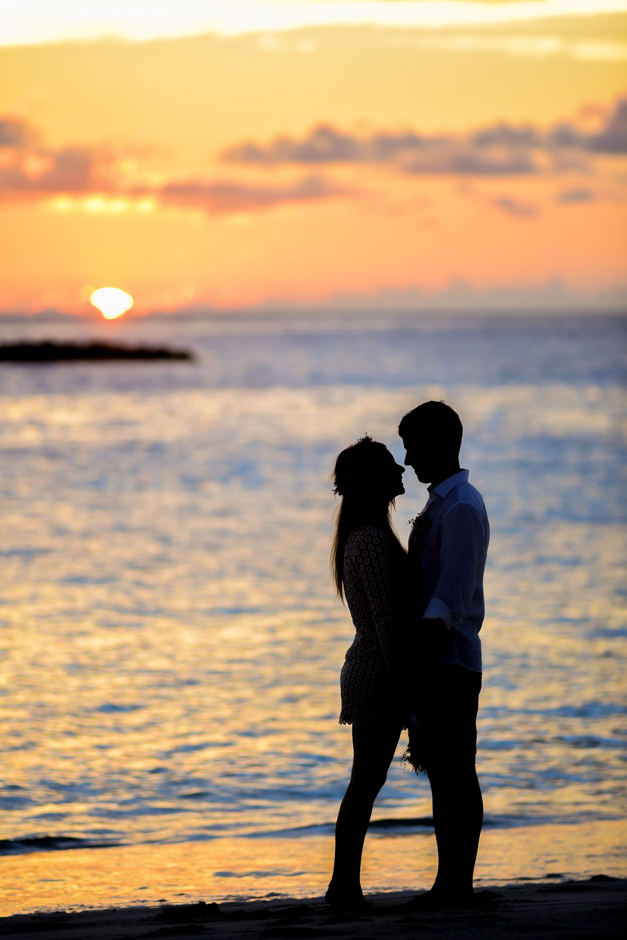 Foto de casal se beijando na beira da praia.