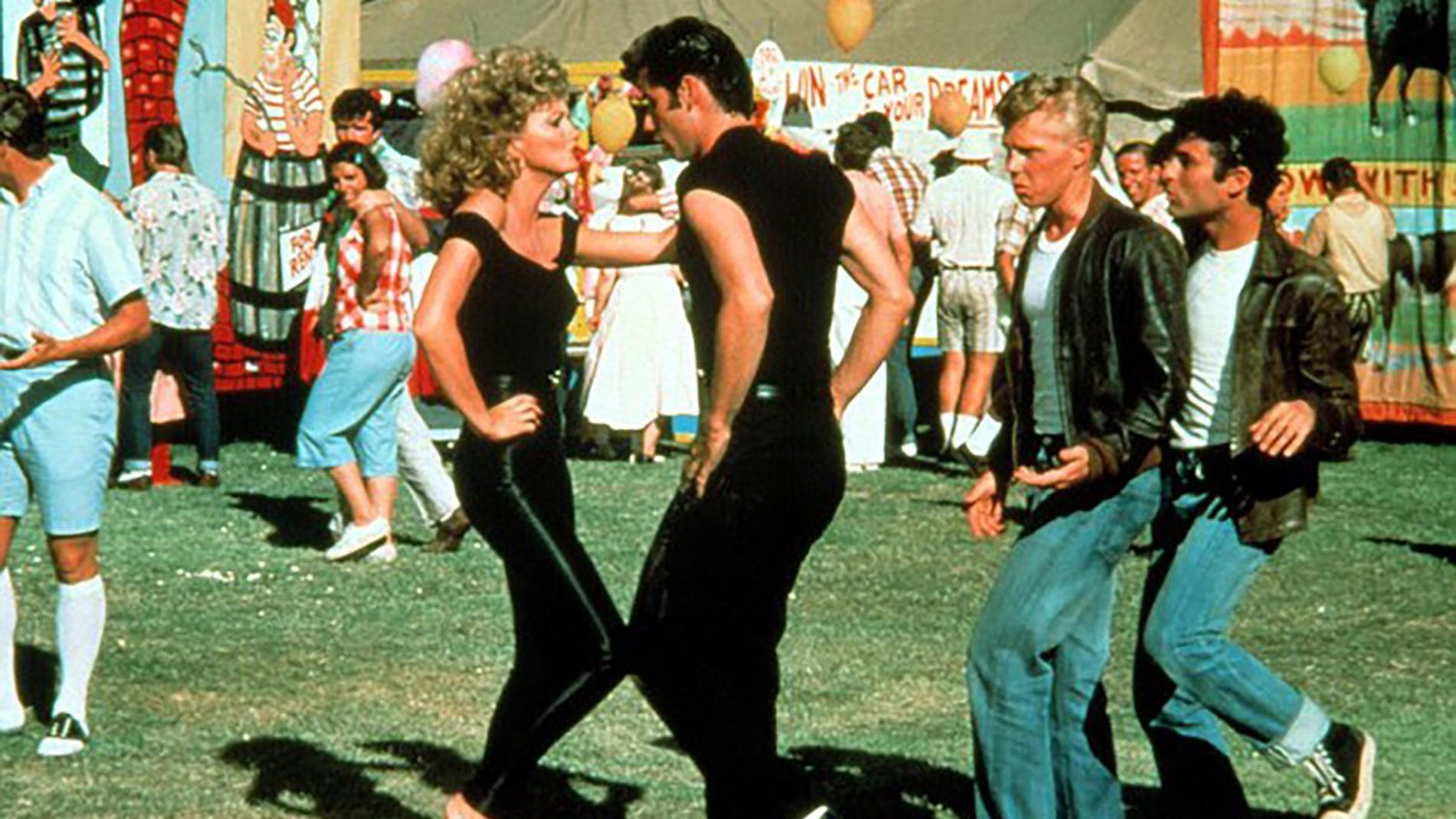 Cena do filme grease, em que john travolta e olivia newton-john estão dançando.