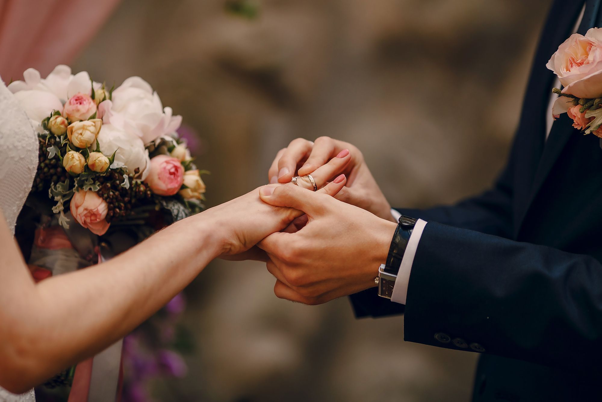 Foto colorida de noivo colocando a aliança na noiva.