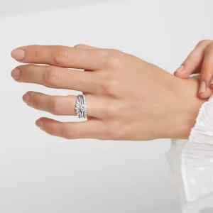 Foto da mão de uma mulher usando três anéis: o de noivado, o de casamento e o da eternidade.