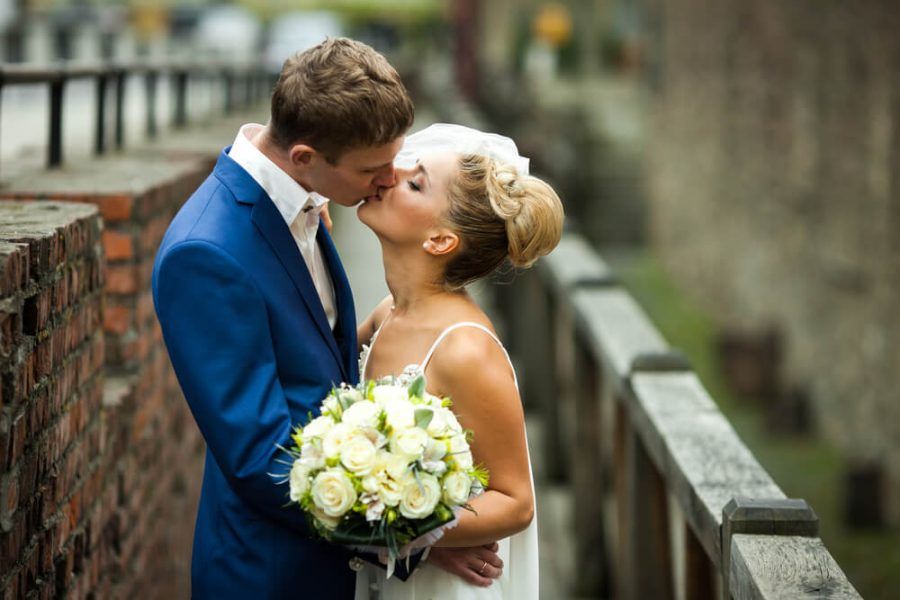 Foto de noivos recém casados se beijando. O noivo está de azul.