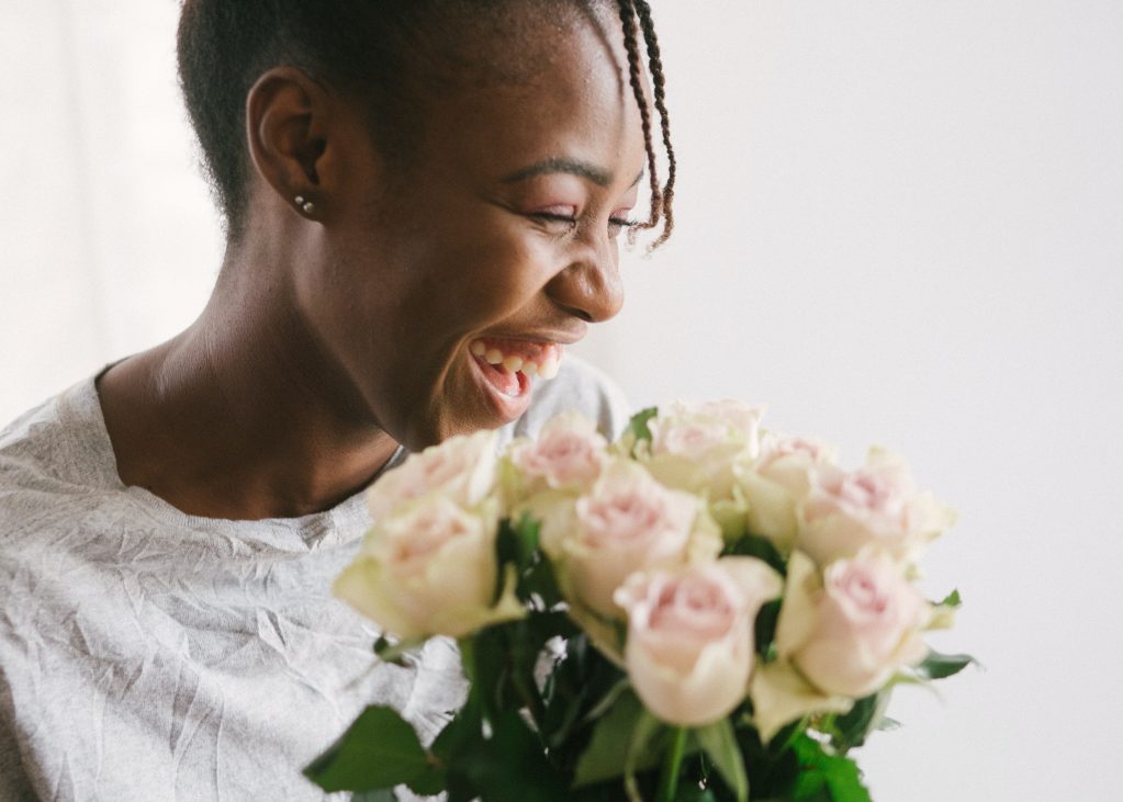 Foto de mulher sorrindo ao segurar um buquê de flores