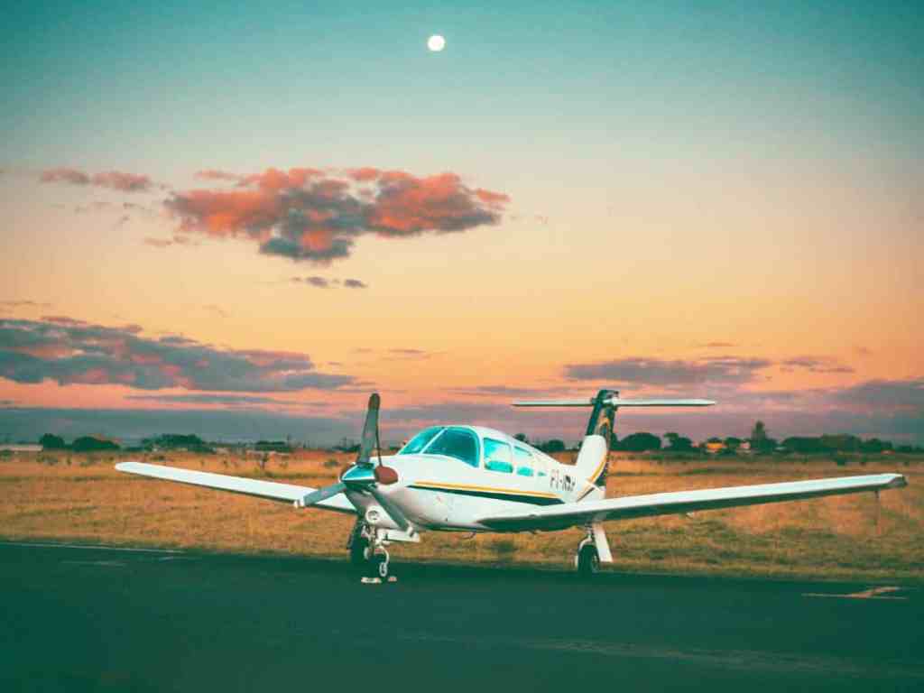 Onde passar a Lua de Mel no Brasil? Confira 5 opções - Aviao-decolando-viagem-lua-de-mel O céu está na cor azul e laranja e pode-se ver a lua. No chão tem o avião branco prestes a decolar.