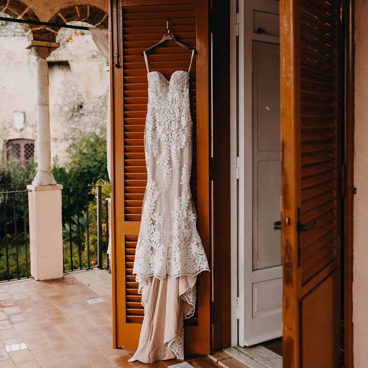 Foto de vestido de noiva pendurado em porta.