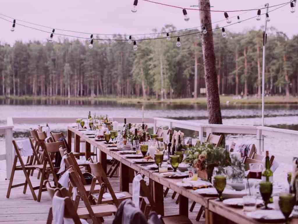 Foto de uma mesa longa na bodas de casamento, com os pratos e taças para os convidados ao ar livre
