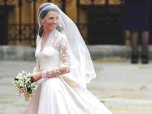Kate middleton sorrindo na calçada, em seu vestido de noiva bordado e usando o véu. Inspire-se neste vestido de casamento real britânico.