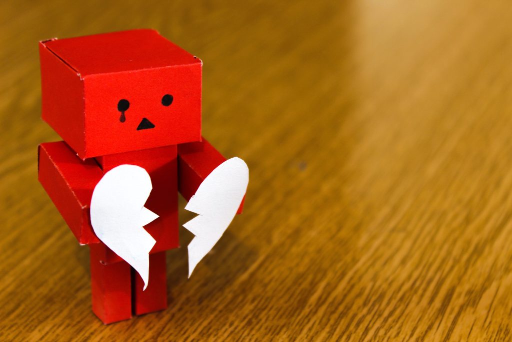 Foto de um robô segurando um coração de papel partido.