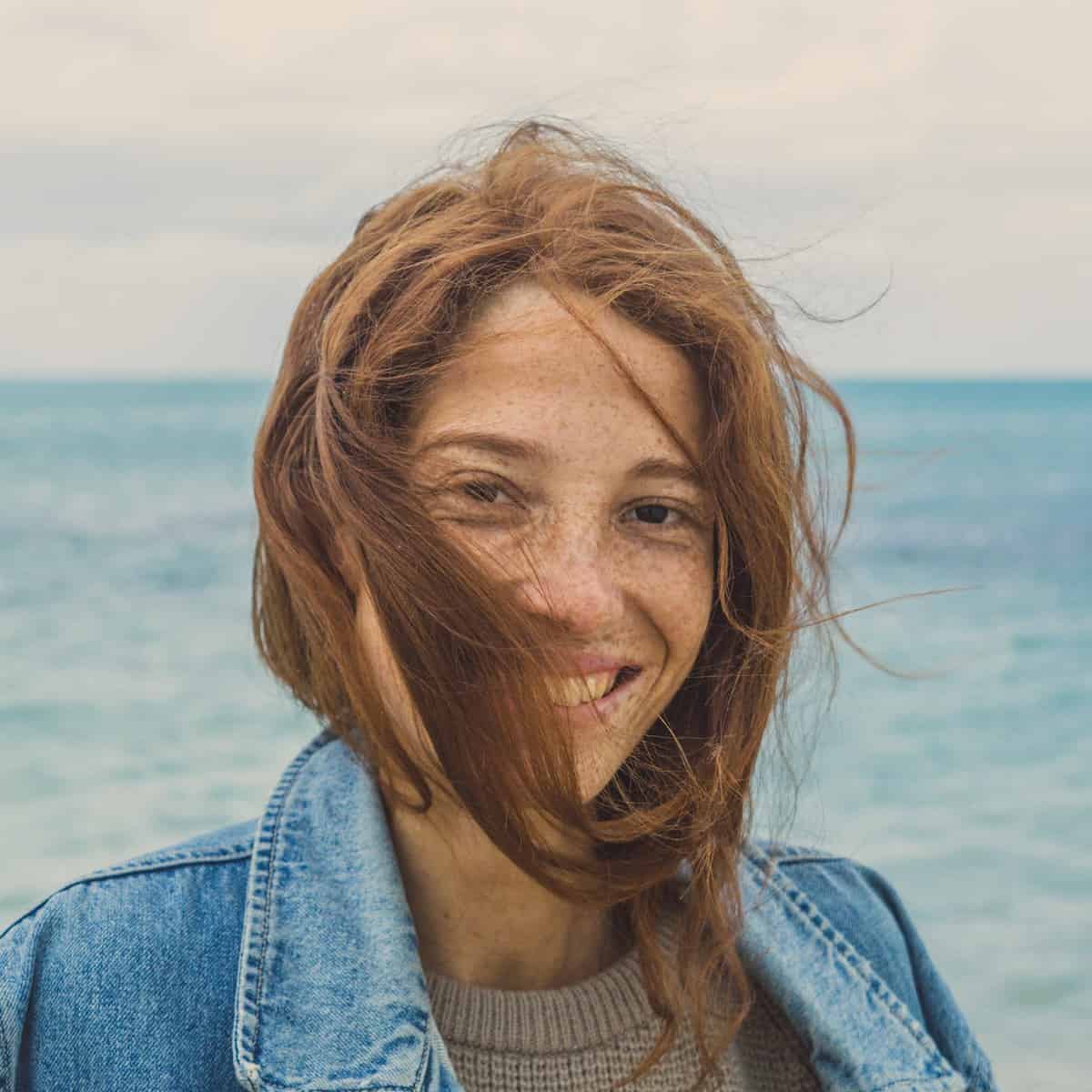 Foto de mulher de costas para o mar e sorrindo