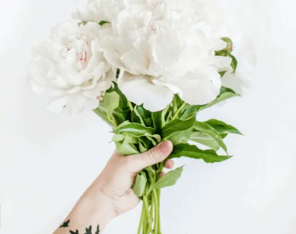 Como escolher o buquê perfeito para o casamento? - Buque-de-casamento Segurando um buquê. Ela tem tatuagens de pássaros no braço.