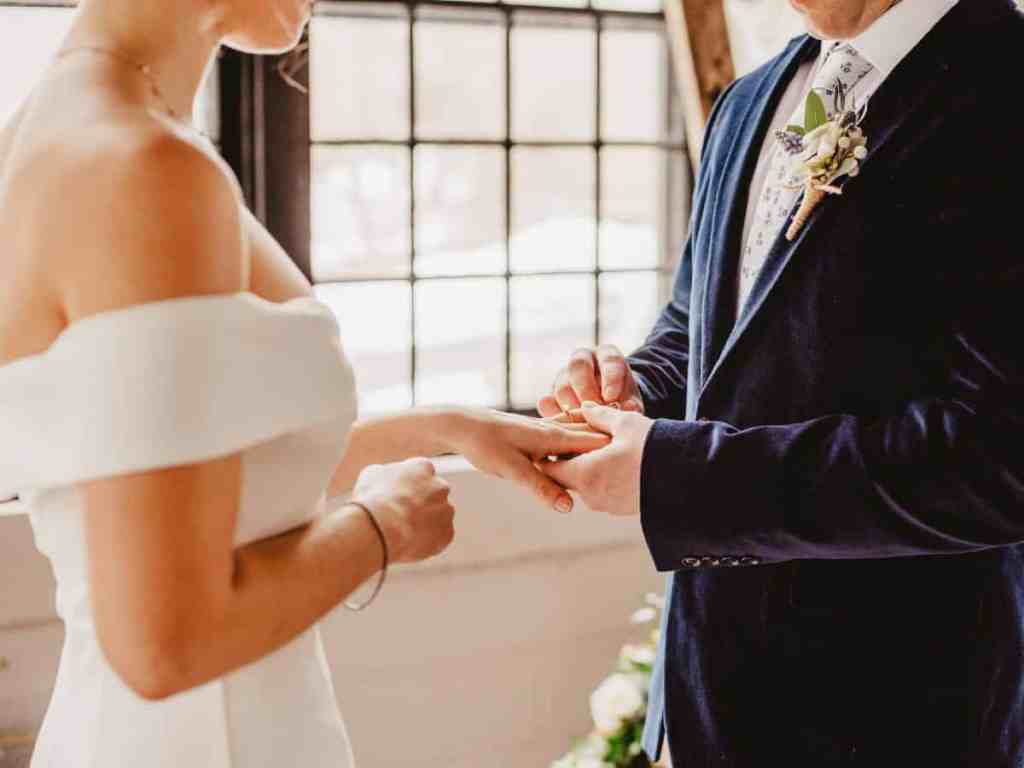 Noivo colocando aliança no dedo da noiva.
