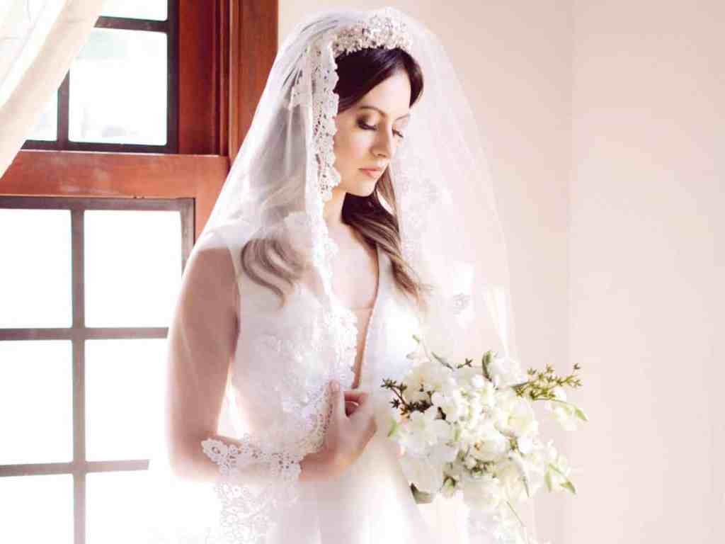O que é uma mantilha? - Noiva-mantilha-grinalda-buque Noiva olhando para o buquê em suas mãos. Ela usa mantilha e tiara branca.