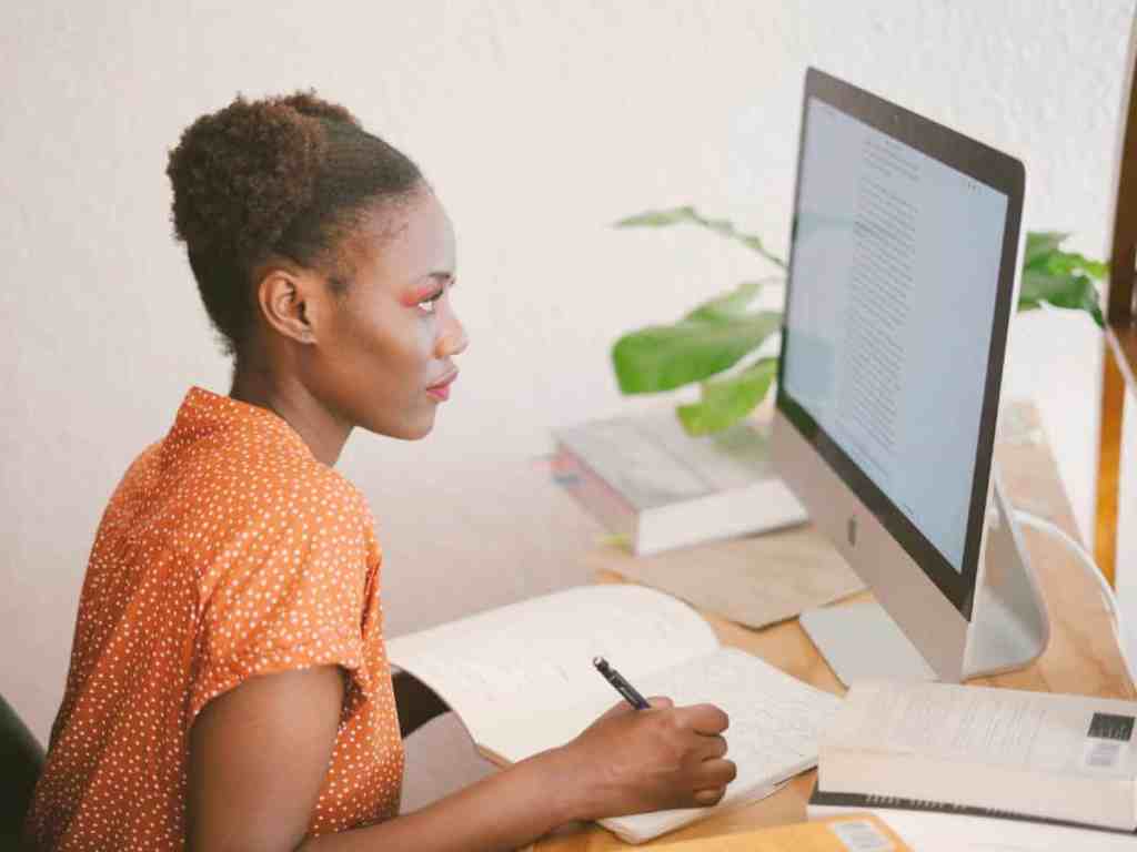 Cursos on-line gratuitos de empreendedorismo - Aprendendo-computador Mulher estudando pelo computador. Ela usa vestido laranja com bolinhas brancas.