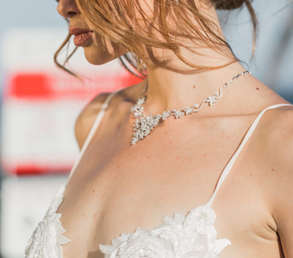 Guia Definitivo das Pedras: Tipos de Cravação e Lapidação - Colar diamantes pedrinhas 1024x901 Mulher com colar, vesti branco de alça e cabelo preso em coque.