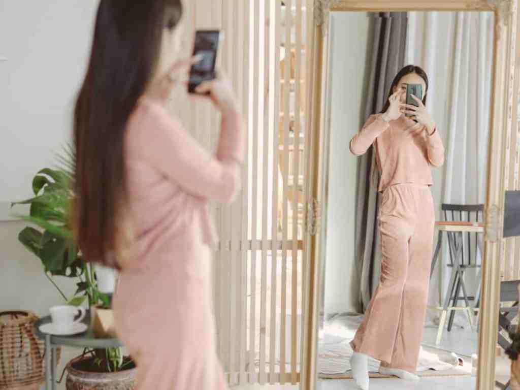 Mulher tirando foto na frente do espelho.