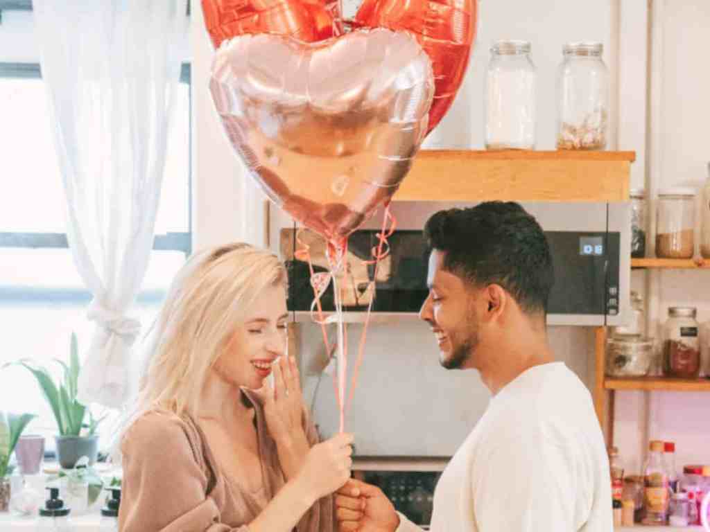 Namorado entregando balão em formato de coração para namorada.