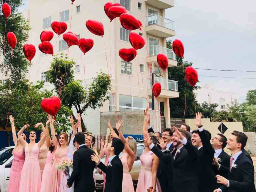 Madrinhas e padrinhos do casamento soltando balões em formato de coração.