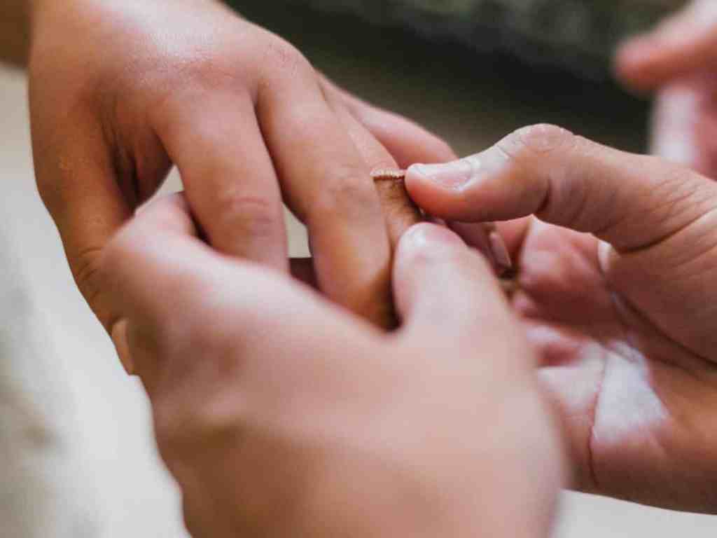 Colocando aliança de ouro rosé no dedo da noiva.