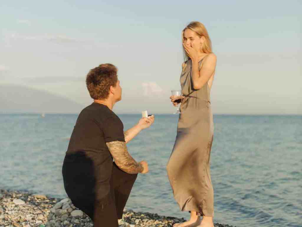 Homem pedindo mulher em casamento na praia.
