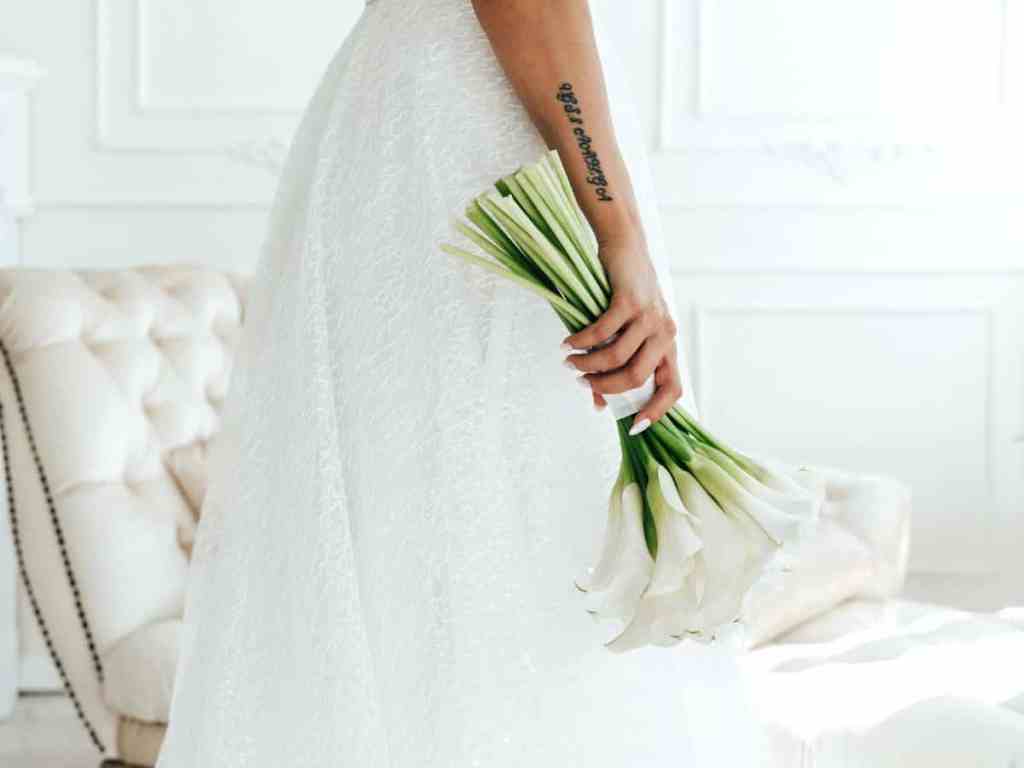 Noiva em pé, segurando um buquê de noiva branco.