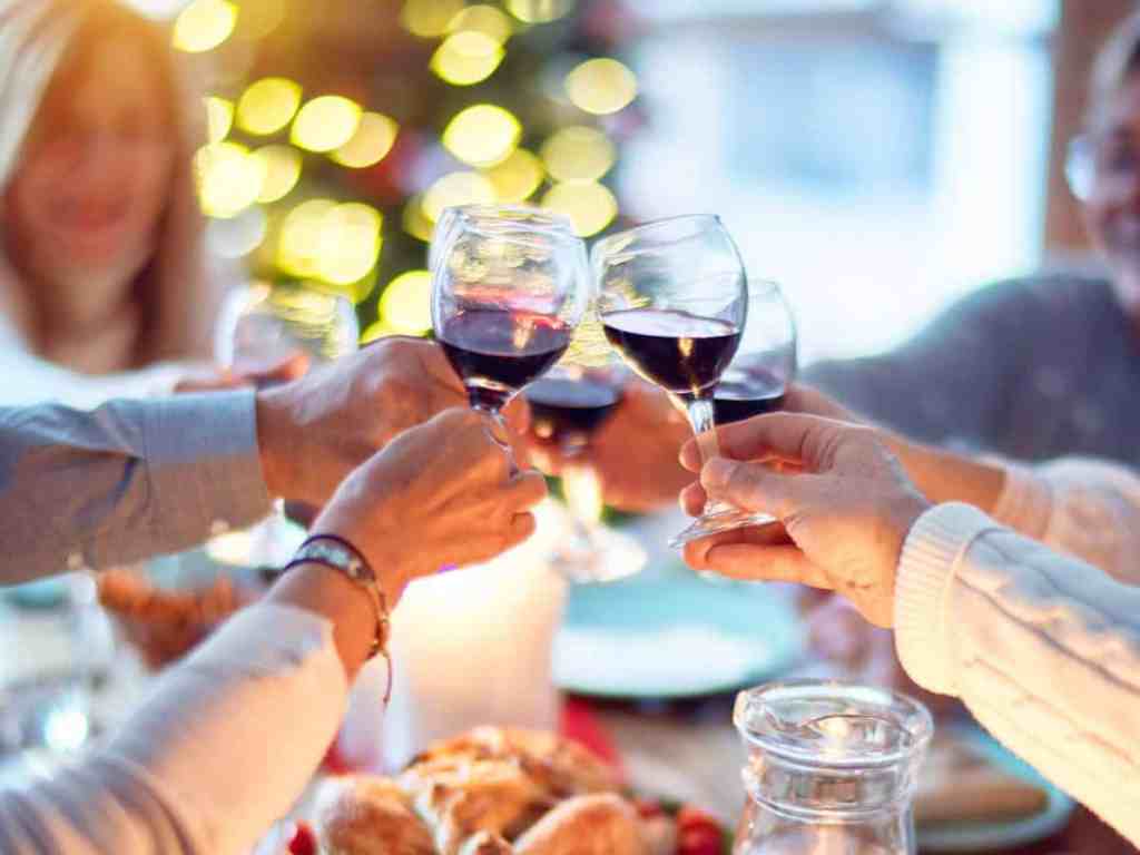 Família brindando com taças de vinho na mesa de jantar.
