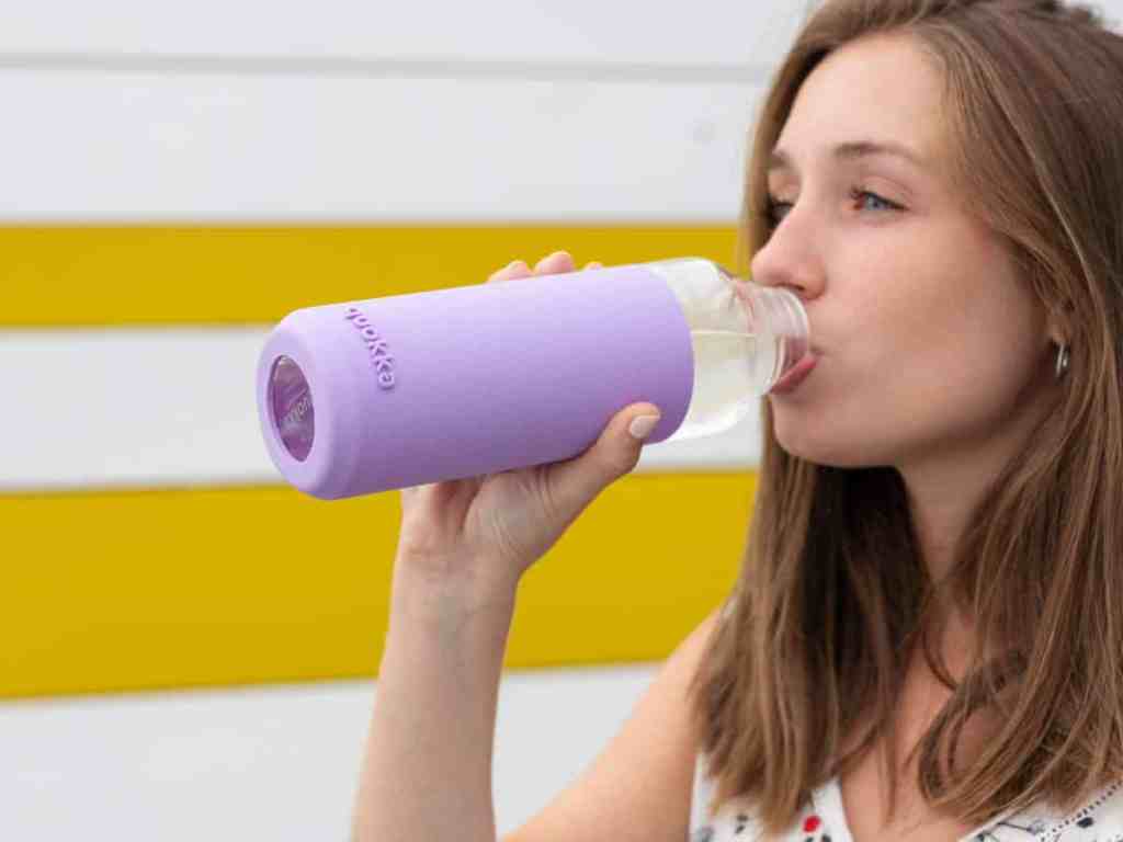 Mulher loira bebendo água.