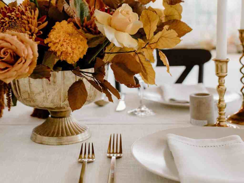 Mesa branca com pratos e buquê de flores