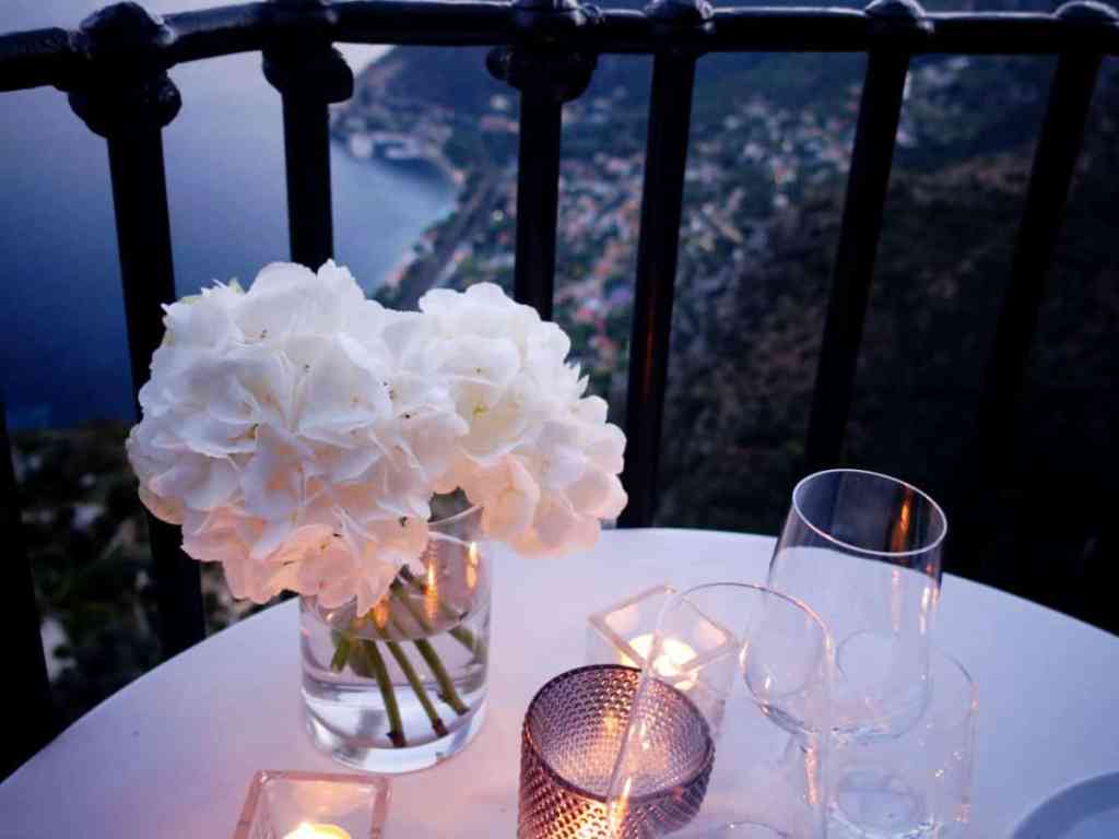 Mesa de jantar com taças, buquê branco e velas