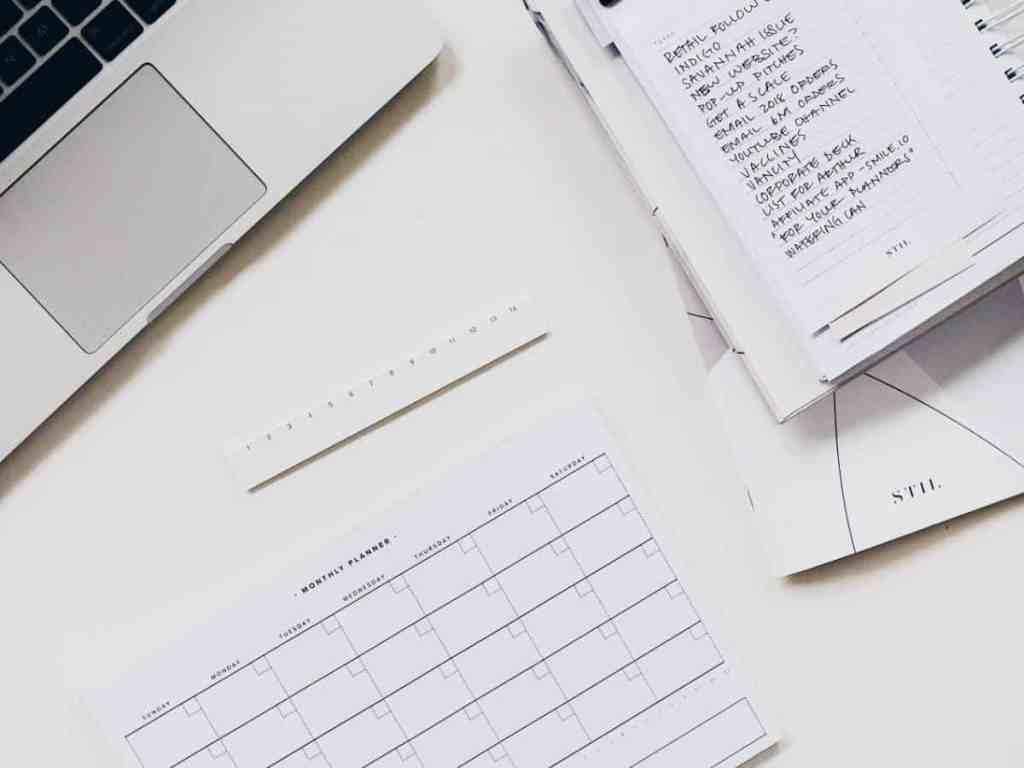 Agenda, planner e notebook em cima de uma mesa branca