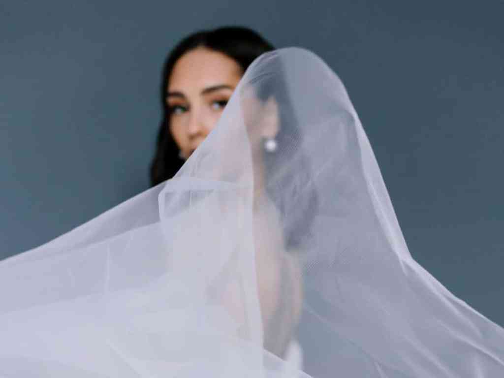 Mulher com o véu de noiva esvoaçante em sua frente