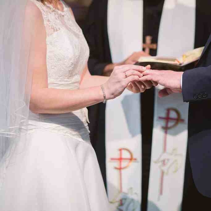 Casamento em uma igreja, os noivos estão virados um para o outro de mãos dadas
