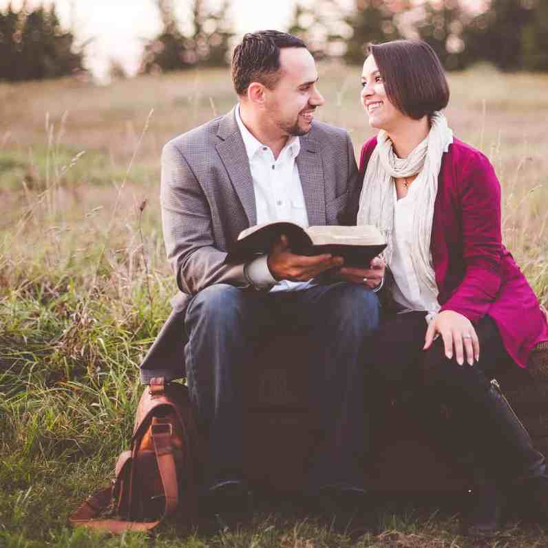 Casal no meio do mato sorrindo enquanto segura bíblia