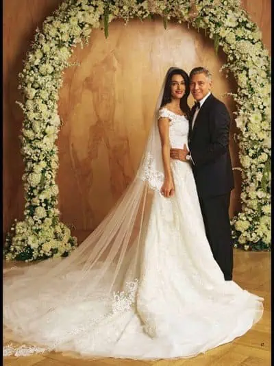 20 casamentos mais caros da história - Casamento-amal-alamuddin-george-clooney-casal George clooney e amal alamuddin em seu casamento, abraçados, posando na frente de um arco de flores
