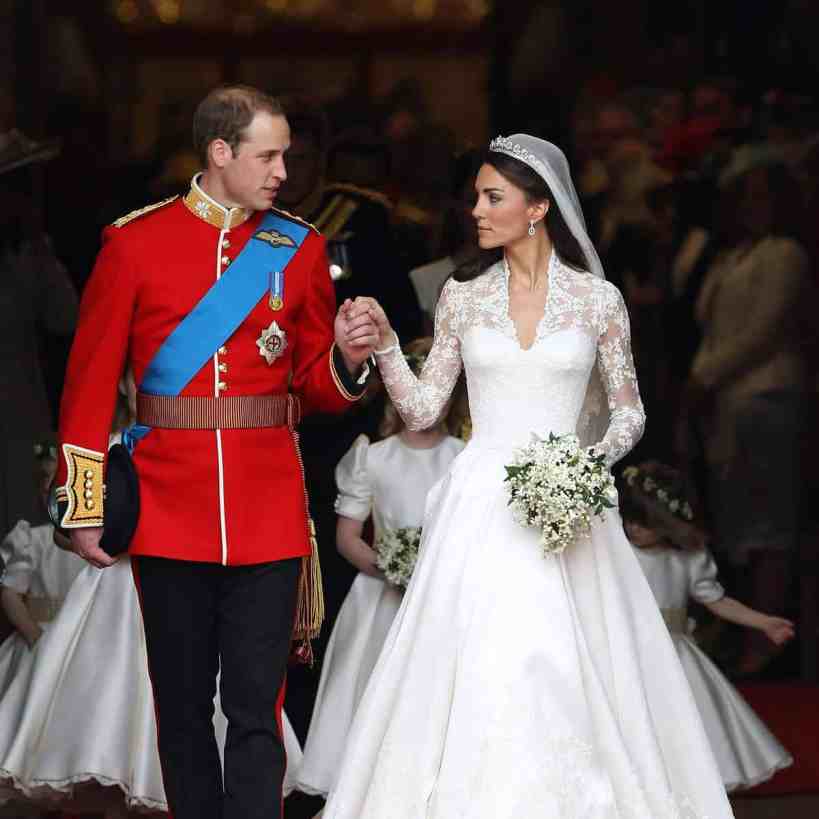 Casamento do príncipe william e kate middleton. Ele veste traje real de príncipe e segura a mão dela ao sair, que veste vestido branco rendado.