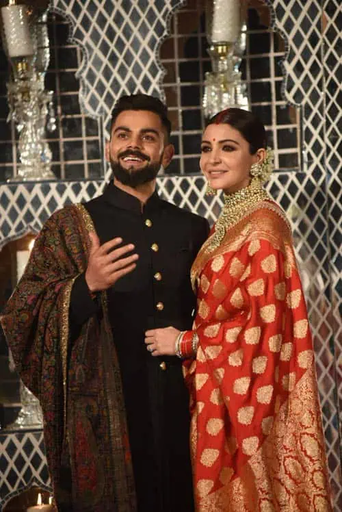 20 casamentos mais caros da história - Casamento-virat-kohli-anushka-sharma-recepcao Virat kohli e anushka sharma em seu casamento. Eles usam roupas típicas indianas. Em que o vestido dela é vermelho estampado.