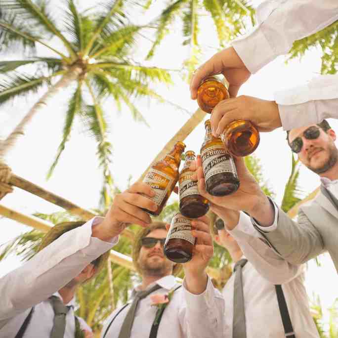 Padrinhos e o noivo brindando garrafas de cerveja