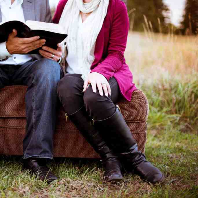 Casal sentado no meio da mata lendo a bíblia