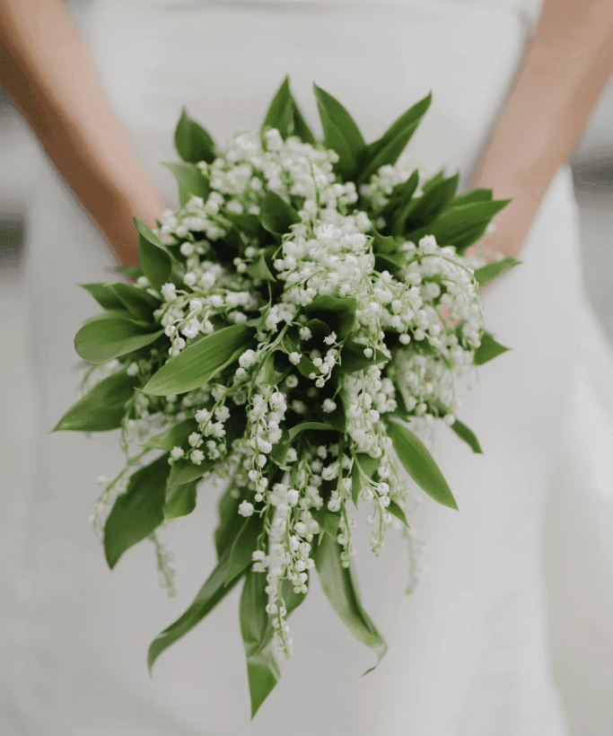 Noiva segurando buquê com folhas e pequenas florzinhas brancas