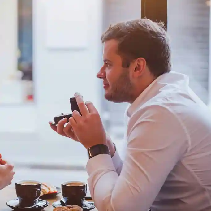 Como começar a falar de casamento? - Casamento-3 Casal sentado tomando café, o homem abre uma caixinha com anel de noivado