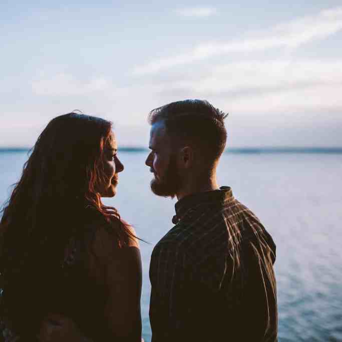 Como começar a falar de casamento? - Conversas-para-antes-do-casamento Casal de homem e mulher olhando um para o outro e frente ao mar
