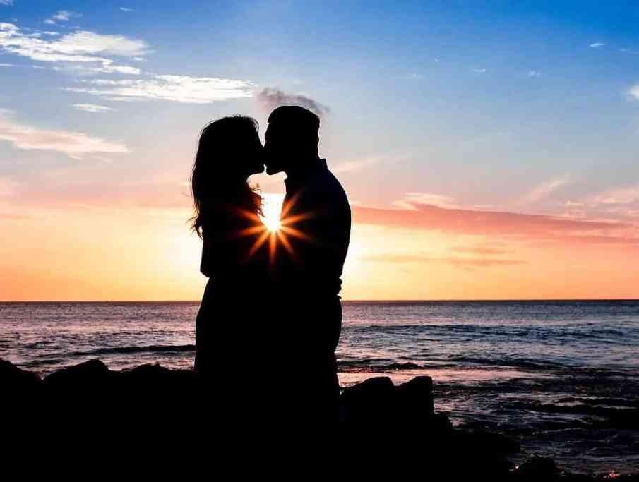 Lua de mel com casal se beijando em frente ao mar