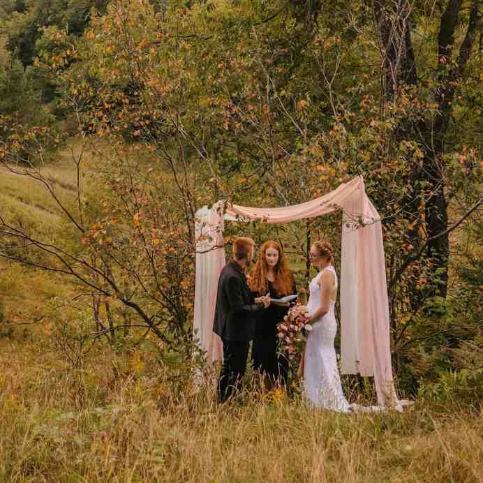 Casal casando no meio da floresta sozinhos, quem está fazendo a cerimônia é uma mulher ruiva