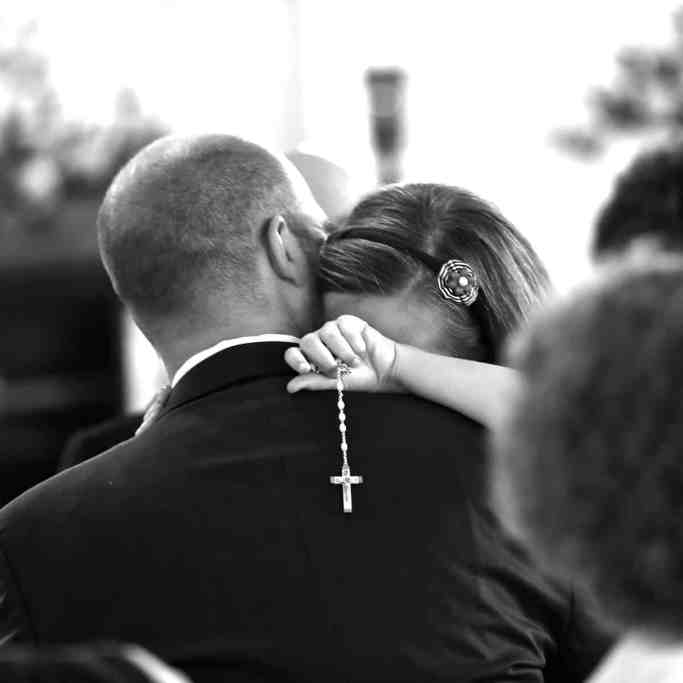 Noiva segurando terço abraçada com pai, imagem em preto e branco