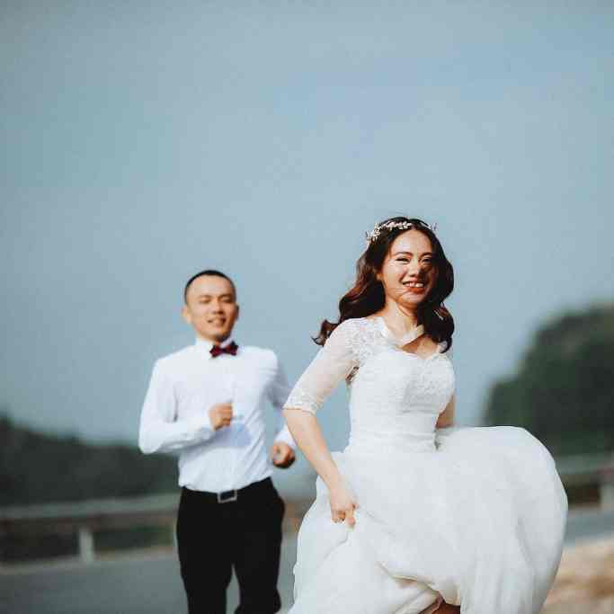 Noiva correndo feliz e noivo correndo atrás dela
