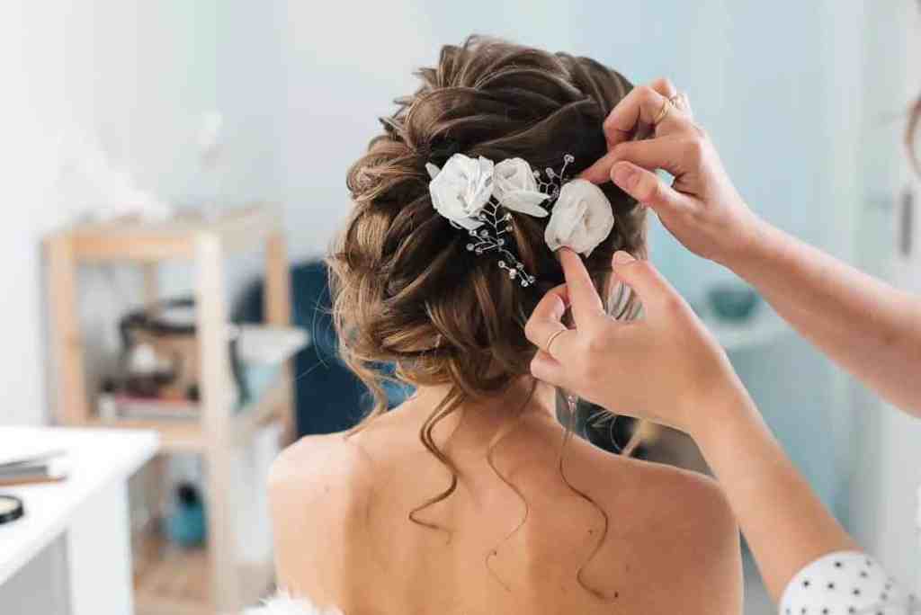 Cabelereira arrumando penteado da noiva com flores