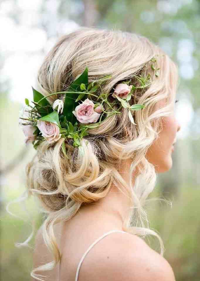 Penteado de coque baixo com flores adornando  para noivas do cabelo longo